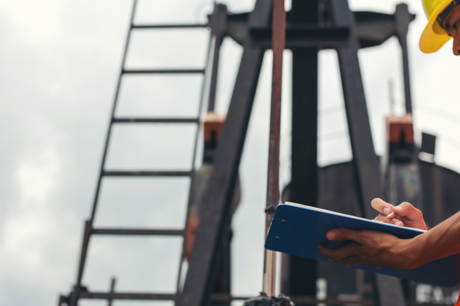 Workers standing and checking beside working oil pumps.